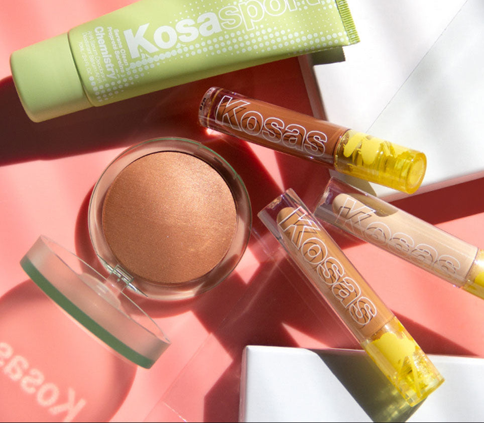 Kosas Cosmetics products including a jar, tube, and container on a pink background